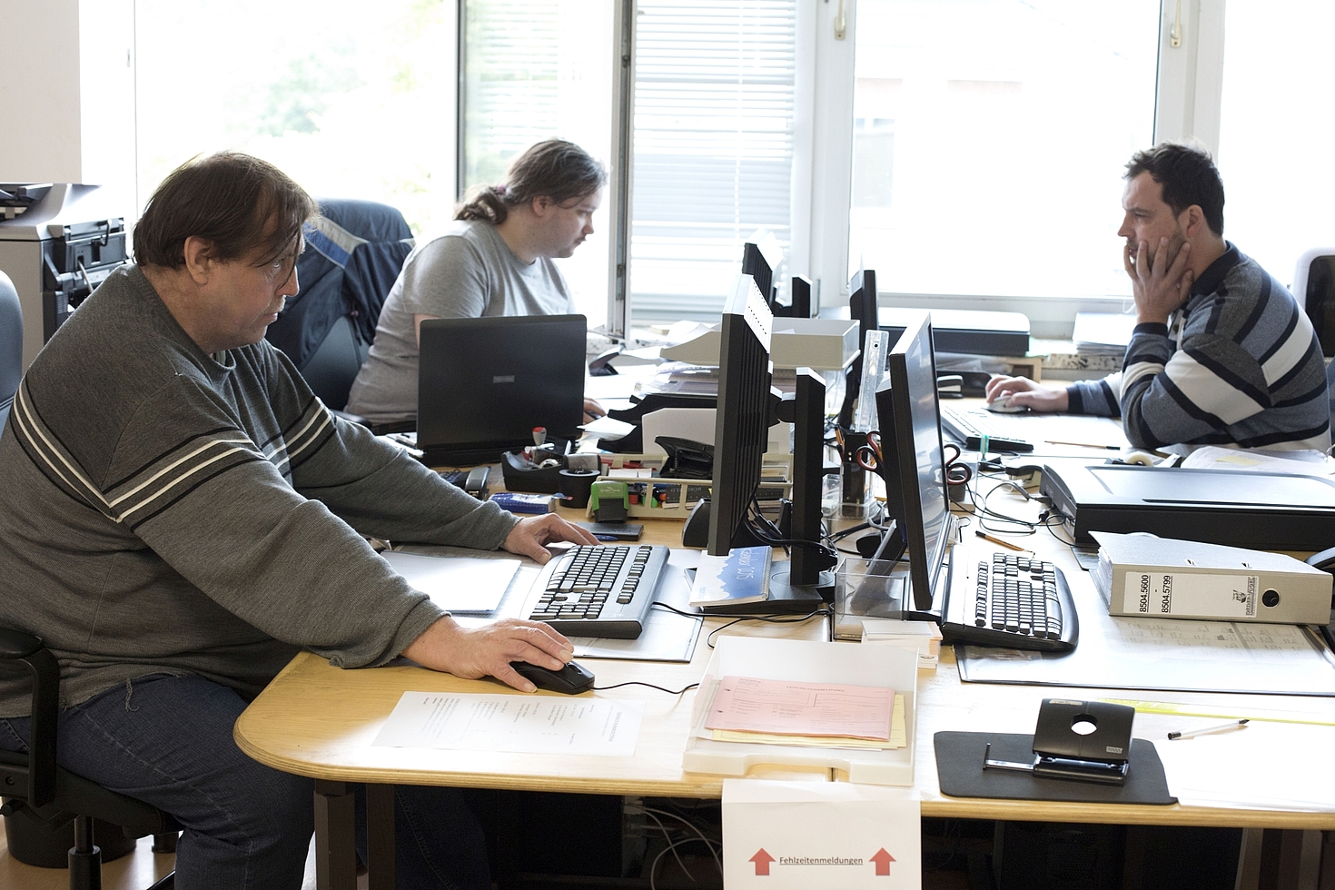 Foto: Zwei Männer und eine Frau arbeiten im Büro am Computer