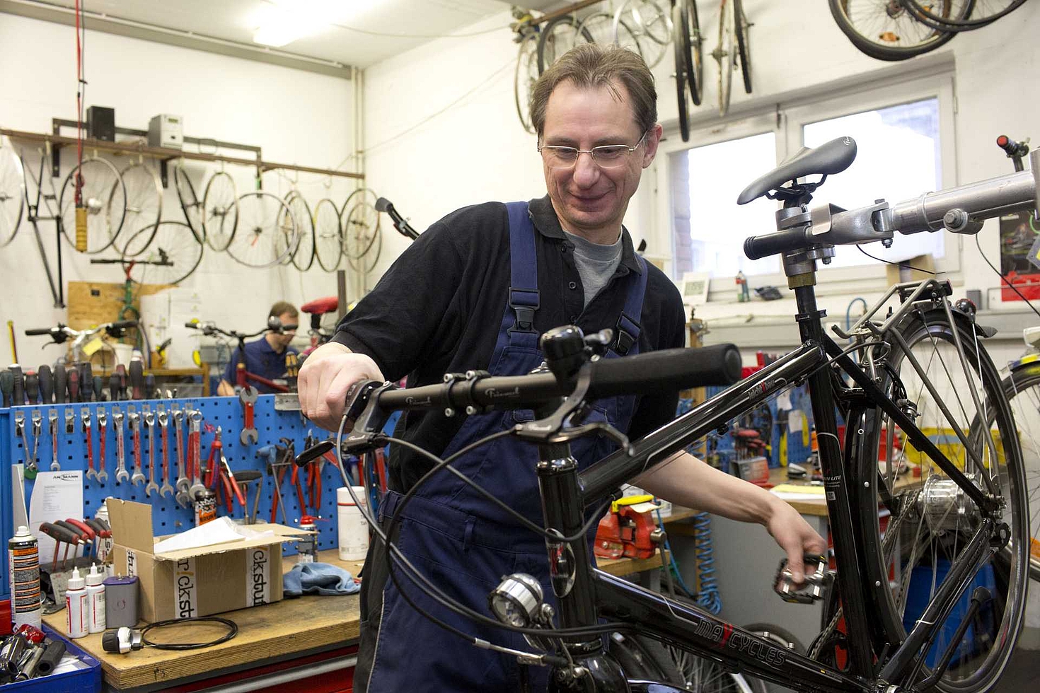 Foto: Mann arbeitet in Werkstatt an einem Fahrrad