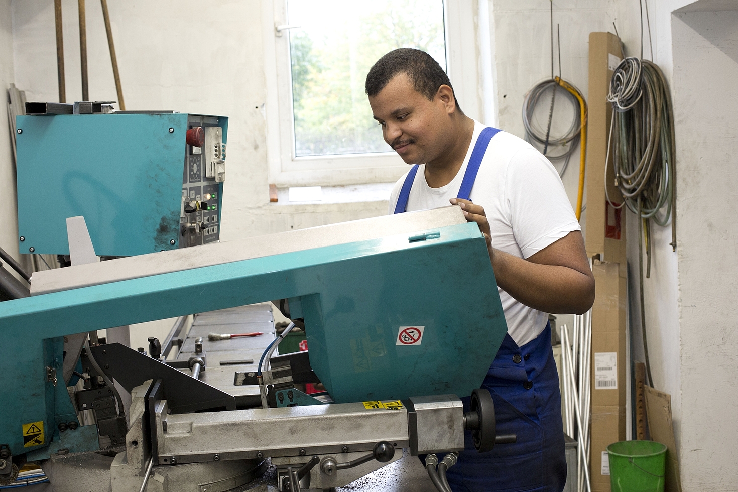 Foto: Mann in Arbeitskleidung bearbeitet Metall mit Maschine